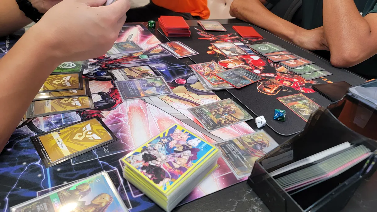 Close-up of a card game table with sleeved cards, playmats and dice