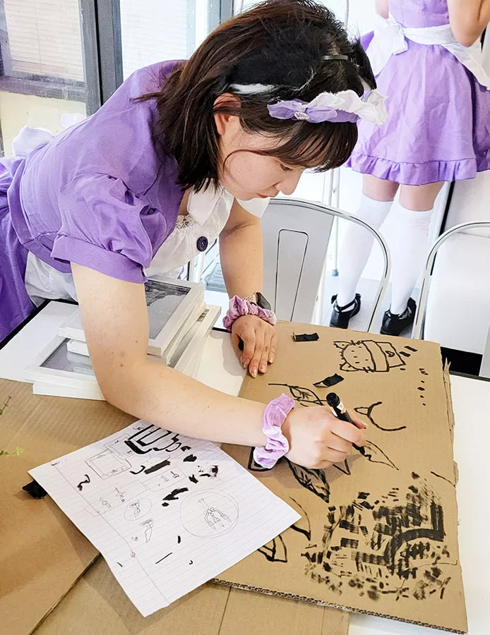 A maid hand-drawing line art during the café renovation