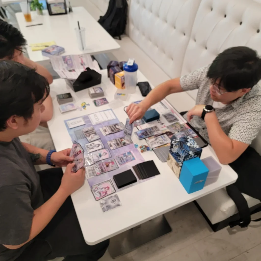 Two players in the middle of a card game at a white café table