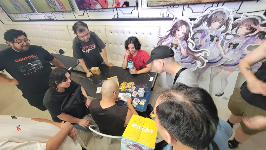 A table of players mid-game next to the maid standees at the café