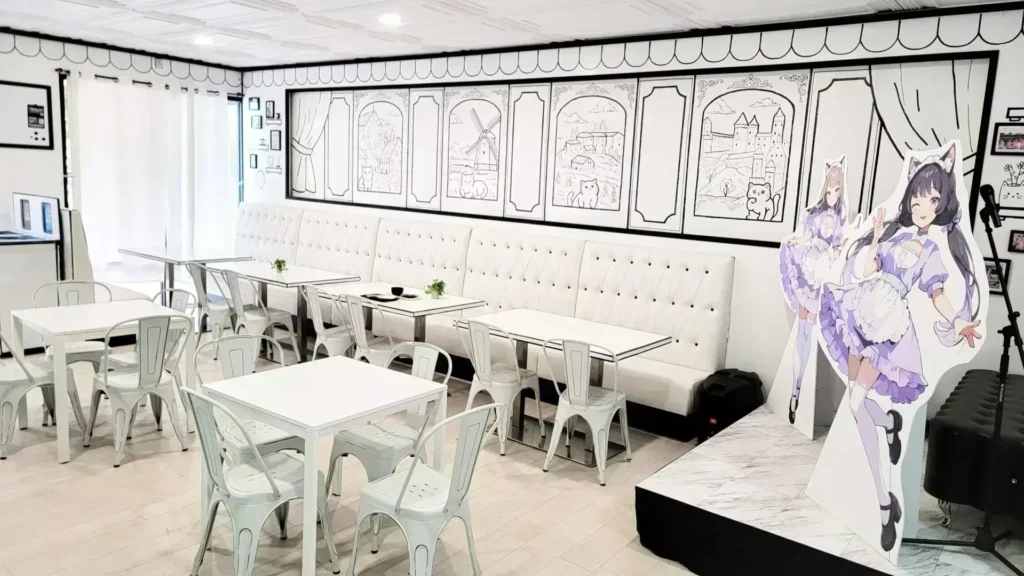 The inside of Arcane Maid Café, with white tables and hand-drawn art on the walls