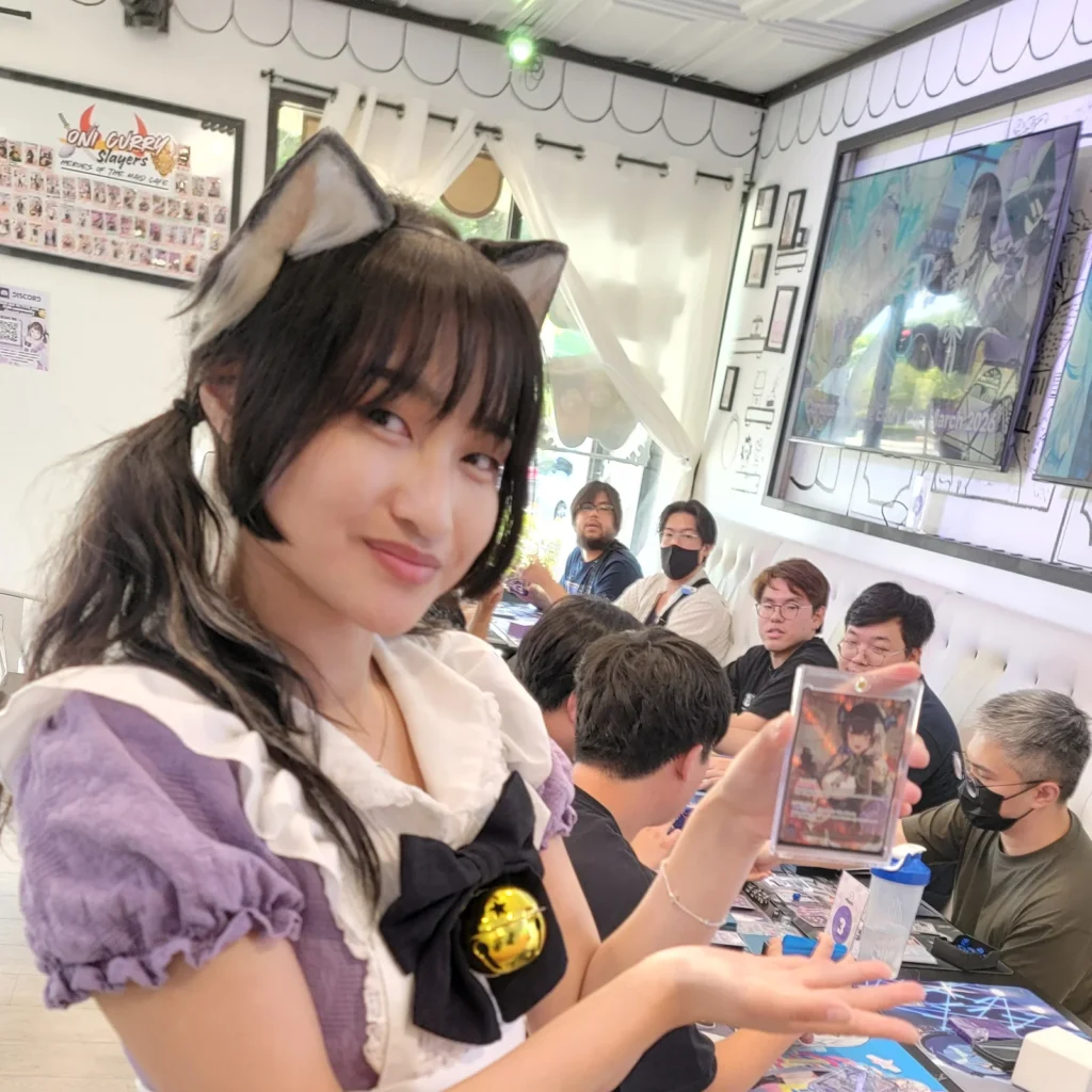 One of the Arcane Maid Café maids showing off a pulled card during a tournament in the café, square crop